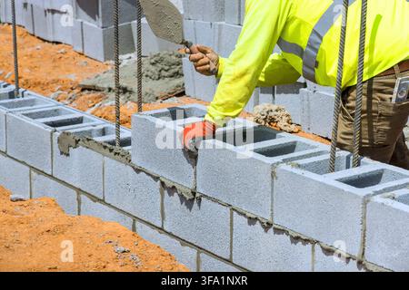 Worker lays concrete blocks in wall at construction site on area materials tools. Stock Photo
