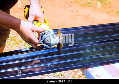 Handyman uses cutting tool on metal sheet in yard sparks fly as tool makes cutting contact Stock Photo