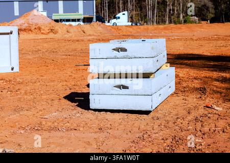 Two concrete blocks are stacked on ground at construction site heavy machinery is nearby. Stock Photo