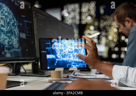 Technician utilizing AI on tablet to optimize performance and forecast issues. IT specialist in tech company office training deep learning models on device to perform automatic updates Stock Photo