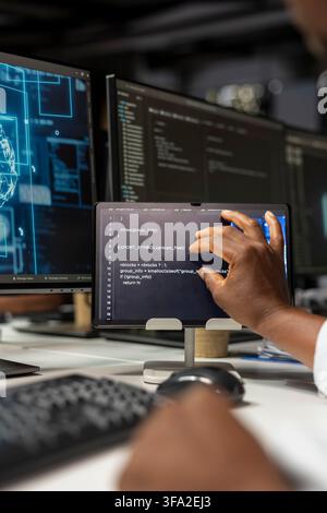Close up of technician using tablet in office, reviewing AI system metrics, monitoring performance dashboards. Tech company IT specialist tuning neural networks using digital device app Stock Photo