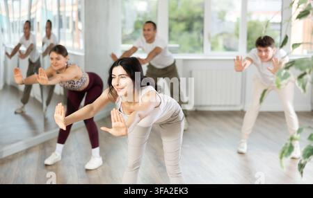 Young brunette warming up with group in dance class Stock Photo