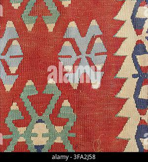 Handwoven kilim rug featuring traditional Anatolian geometric patterns with vibrant red, blue, green, and cream colors, showcasing ethnic textile art Stock Photo