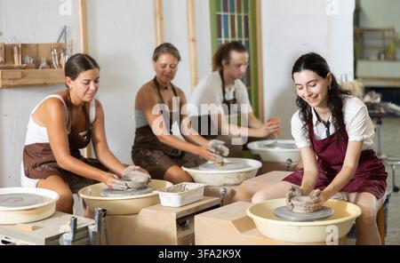 Young woman sits near potter wheel and makes clay crafts Stock Photo