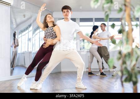 Group of young active sports people practicing rock and roll dance in dance hall Stock Photo