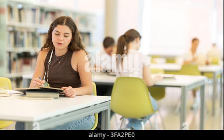 Female student sitting at table and writing Stock Photo