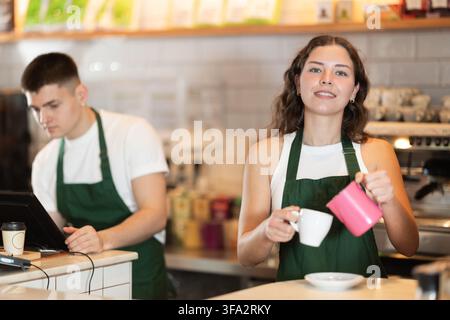 Two baristas making coffee standing near the counter in a cafe Stock Photo