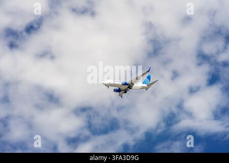 Tustin, CA, USA - August 7, 2026: A United Airlines airplane in flight with landing gears out against a blue cloudy sky coming in for a landing. Stock Photo