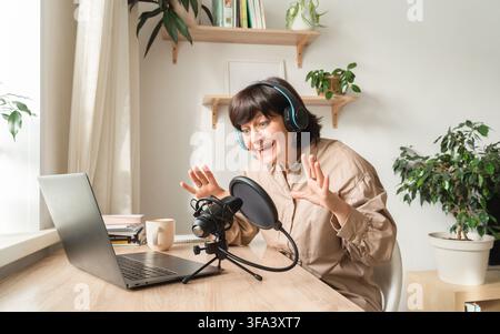 Woman enthusiastically podcasting from home studio Stock Photo