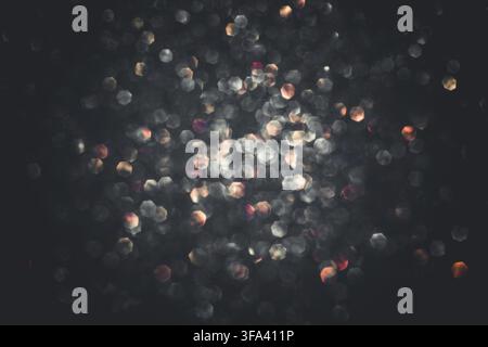 Abstract glitter lights textured multi-colored and black or dark gray background, de-focused, bokeh. Christmas or New Year festive blured sparkling ba Stock Photo