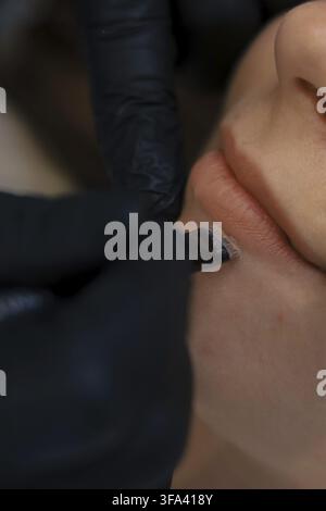 Detailed view of a technician applying lip tattoo procedure, focusing on precision Stock Photo