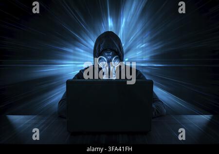 Male thief in gas mask stealing data from computer Stock Photo