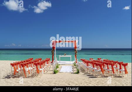 Romantic Wedding setting up with red decorations on the beach Stock Photo