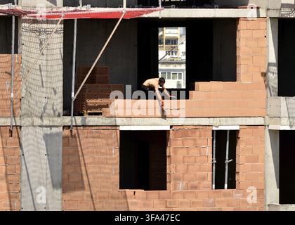 Bricklayer worker or brick mason is laying bricks at a construction site in Sofia Bulgaria, Eastern Europe, Balkans, EU Stock Photo