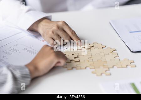 Businessman hands putting together puzzle pieces with Team Building join together and Business Collaboration Concept in office Stock Photo