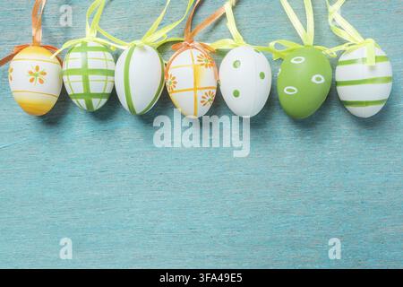 A row of five colorful easter eggs on a blue wooden table Stock Photo