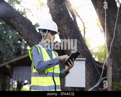 Asian electrical engineer using tablet for monitoring power system digital technology representing smart energy management and sustainable future Stock Photo