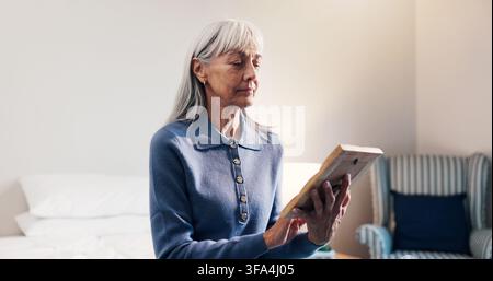 Thinking, photo frame elderly woman in home with memories, nostalgia and lonely in retirement. Senior widow, reflection and picture in bedroom for Stock Photo