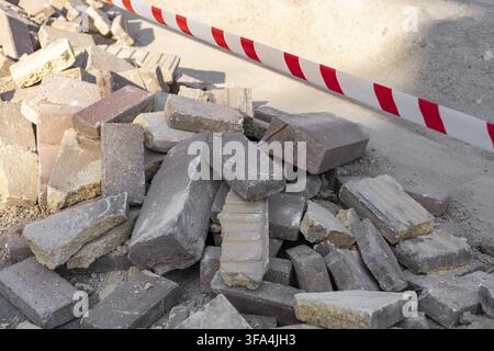 A pile of construction bricks next to a red and white caution tape Stock Photo