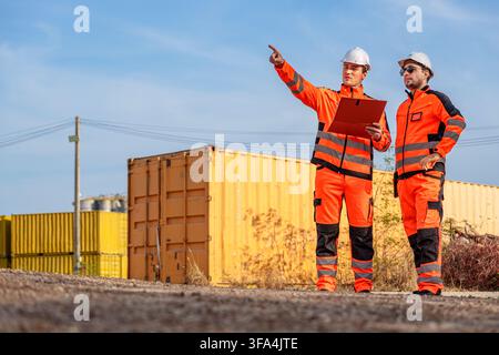 Two engineers discussing project details at a construction site to ensure quality and efficiency. Suitable for construction, engineering, project mana Stock Photo