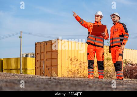 Two engineers discussing project details at a construction site to ensure quality and efficiency. Suitable for construction, engineering, project mana Stock Photo
