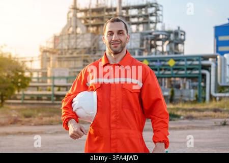 Male worker in safety uniform holding a helmet at an industrial site during maintenance work. Ideal for health and safety, industry, workforce, and en Stock Photo