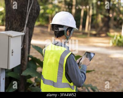Asian electrical engineer using tablet for monitoring power system digital technology representing smart energy management and sustainable future Stock Photo