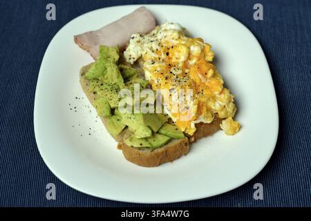 Healthy and nutritious breakfast with scrambled eggs and smashed avocado on toast from above Stock Photo