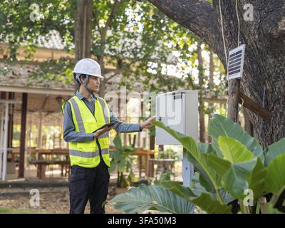 Asian electrical engineer using tablet for monitoring power system digital technology representing smart energy management and sustainable future Stock Photo