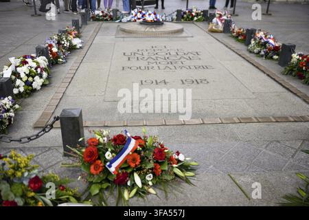 Fresh red and white flowers arranged in a bouquet with green leaves and tricolor ribbon placed on a stone surface in daylight Stock Photo