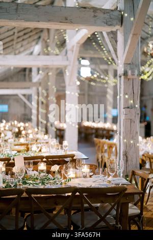 Rustic wedding dinner setup in decorated barn Stock Photo