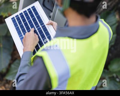 Asian electrical engineer working outdoors with solar panels for clean energy project installing solar panels renewable energy and sustainable power s Stock Photo