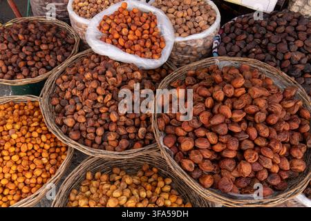 Various types of dried fruit and dates arranged in traditional wicker baskets at a market in Samarkand, Uzbekistan. Stock Photo
