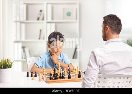 Kid playing a chess game against an adult man Stock Photo