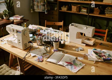Sewing Machines and Craft Supplies on Wooden Table in Creative Workshop Stock Photo