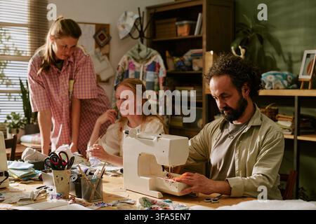 Man and Women Working on Sewing Machine in Creative Workshop Stock Photo