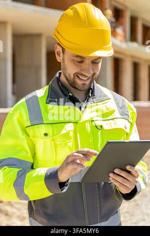 Smiling architectural worker typing on digital tablet computer Stock Photo
