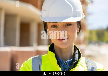 Attractive female architect wearing safety helmet looking at camera Stock Photo