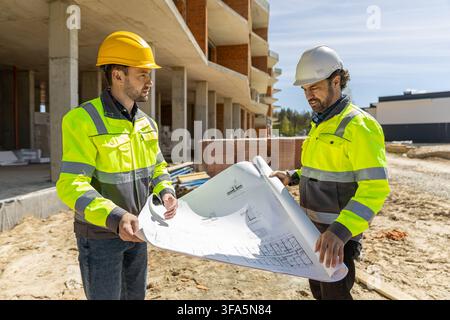 Two male architects wearing safety helmets holding blueprints Stock Photo