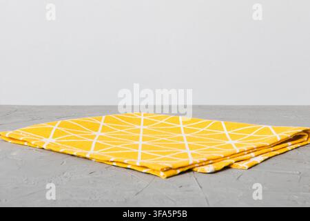 top view with yellow empty kitchen napkin isolated on table background. Folded cloth for mockup with copy space, Flat lay. Minimal style. Stock Photo