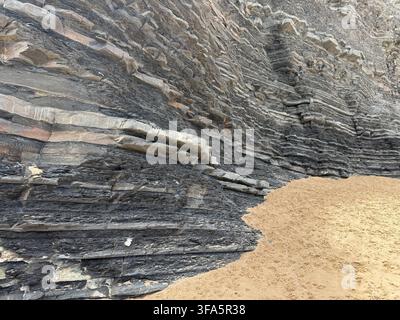 Layered Rock Strata Cliff Face Meeting Sandy Beach Stock Photo