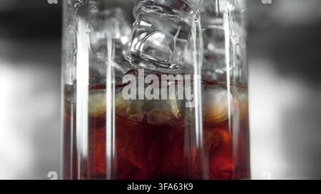 Refreshing iced drink with falling ice cubes in a close-up, illustrating coolness and refreshment on a hot day Stock Photo