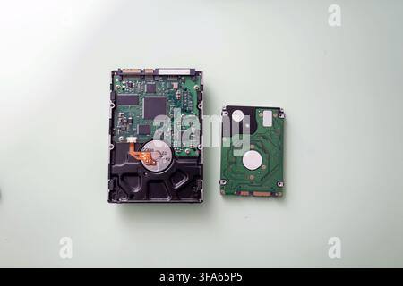 Two parts of a hard drive are placed on a light surface. One part is the main housing, and the other part is a smaller component lying next to it. The Stock Photo