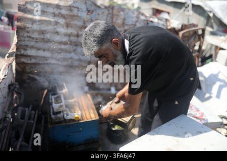 Palestinian beekeeper Nevin al-Ashqar, 43, and her husband Hussein al-Ashqar tend to a beehive on the roof of their damaged home in the Jabalia refugee camp, northern Gaza Strip, on August 18, 2026. Al-Ashqar inherited beekeeping from her father and had managed four apiaries with her husband before the war destroyed most of them. After returning home following displacement, she found one hive still alive and is now trying to resume her work to support her family despite shortages of equipment and the lack of a suitable place, amid widespread damage to the environment and infrastructure in the Stock Photo