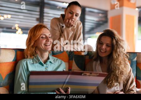 Businesswomen collaborating in a modern cafe while reviewing a project during a productive afternoon meeting Stock Photo