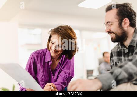 Two businesspeople engaging in a discussion about project plans in a modern office setting during a weekday morning Stock Photo