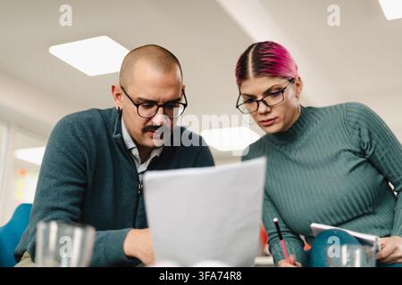 Collaborative discussion between two business professionals in a modern office setting during the afternoon Stock Photo