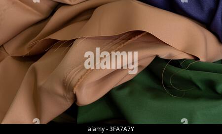 Highly detailed macro perspective of a folded delicate peach fabric revealing an authentic stitched seam and a raw frayed edge with trailing loose thr Stock Photo