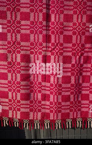 Close-up texture of a traditional Greek handwoven woolen textile in vibrant red and white. Intricate geometric folk art pattern. Stock Photo