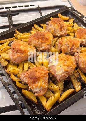 Roasted potatoes and chicken legs on baking sheet, traditional family dinner with crispy vegetables and meat. High quality photo Stock Photo
